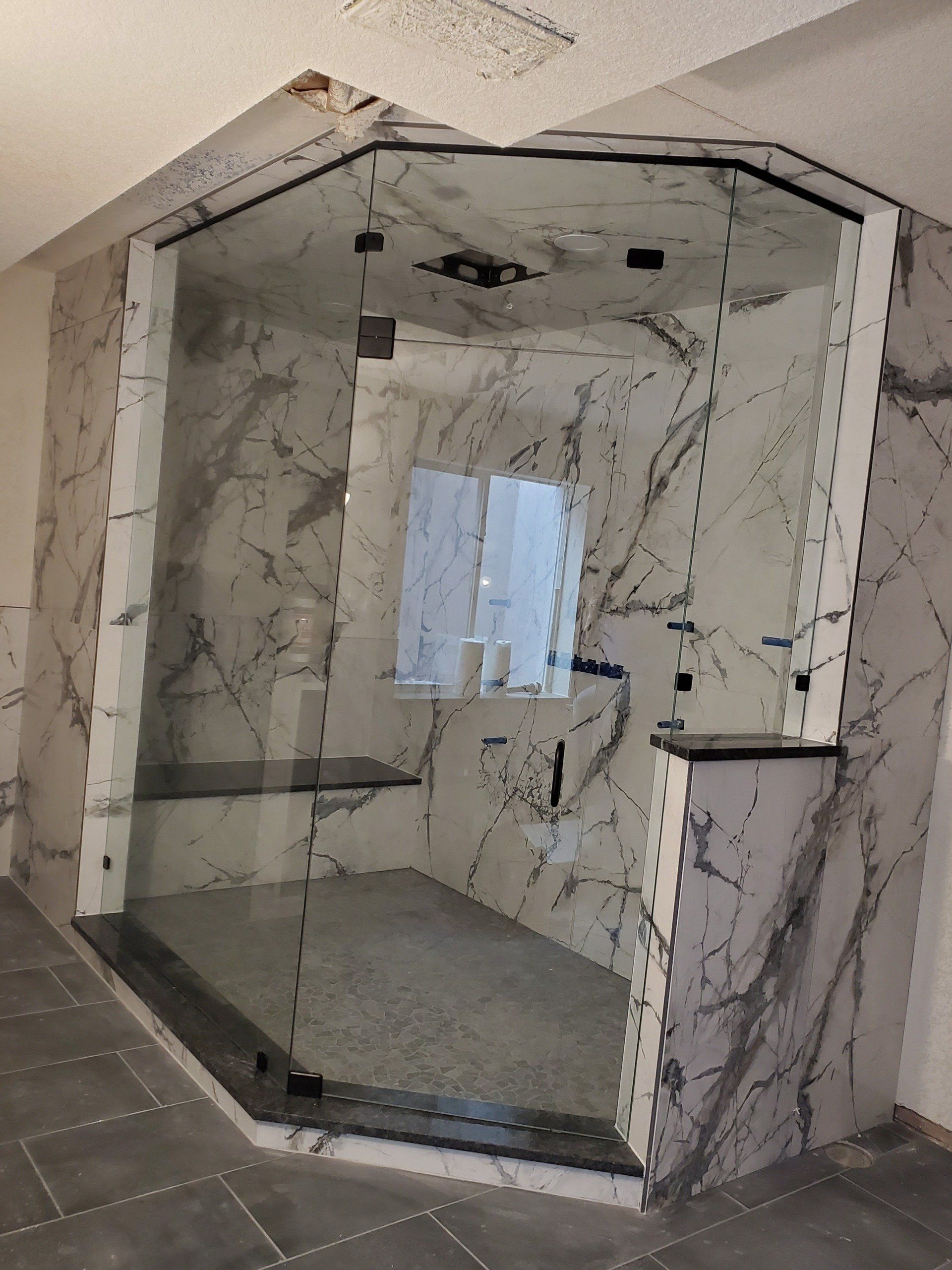 A bathroom with marble walls and a glass shower door.