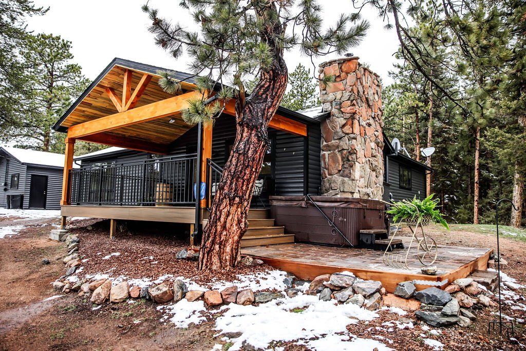 A cabin with a fireplace and a hot tub in the woods.