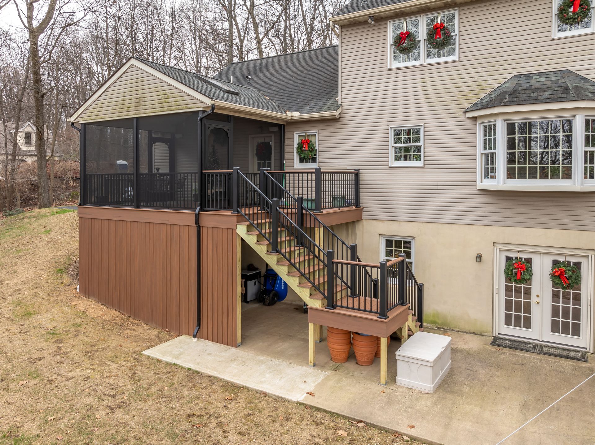 House exterior with screened porch, wooden deck stairs, and festive wreath decorations