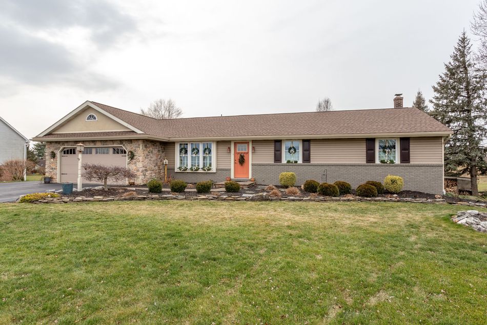 Single-story beige suburban house with a front lawn and stone landscaping