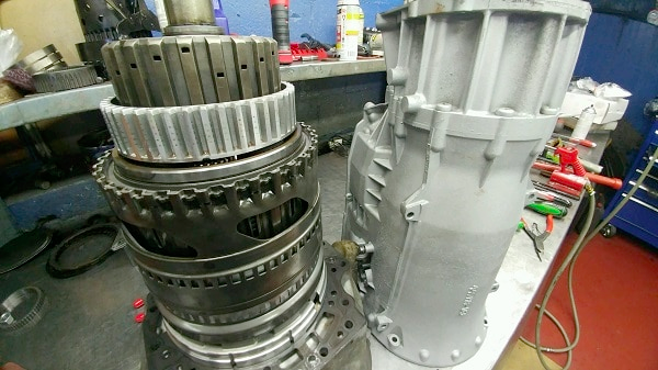 Two gearboxes are sitting on a table in a garage.