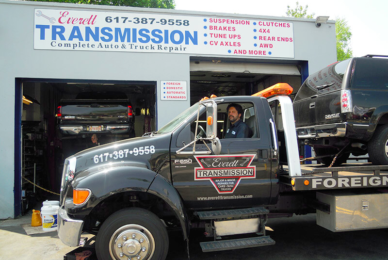 A tow truck is parked in front of a transmission shop