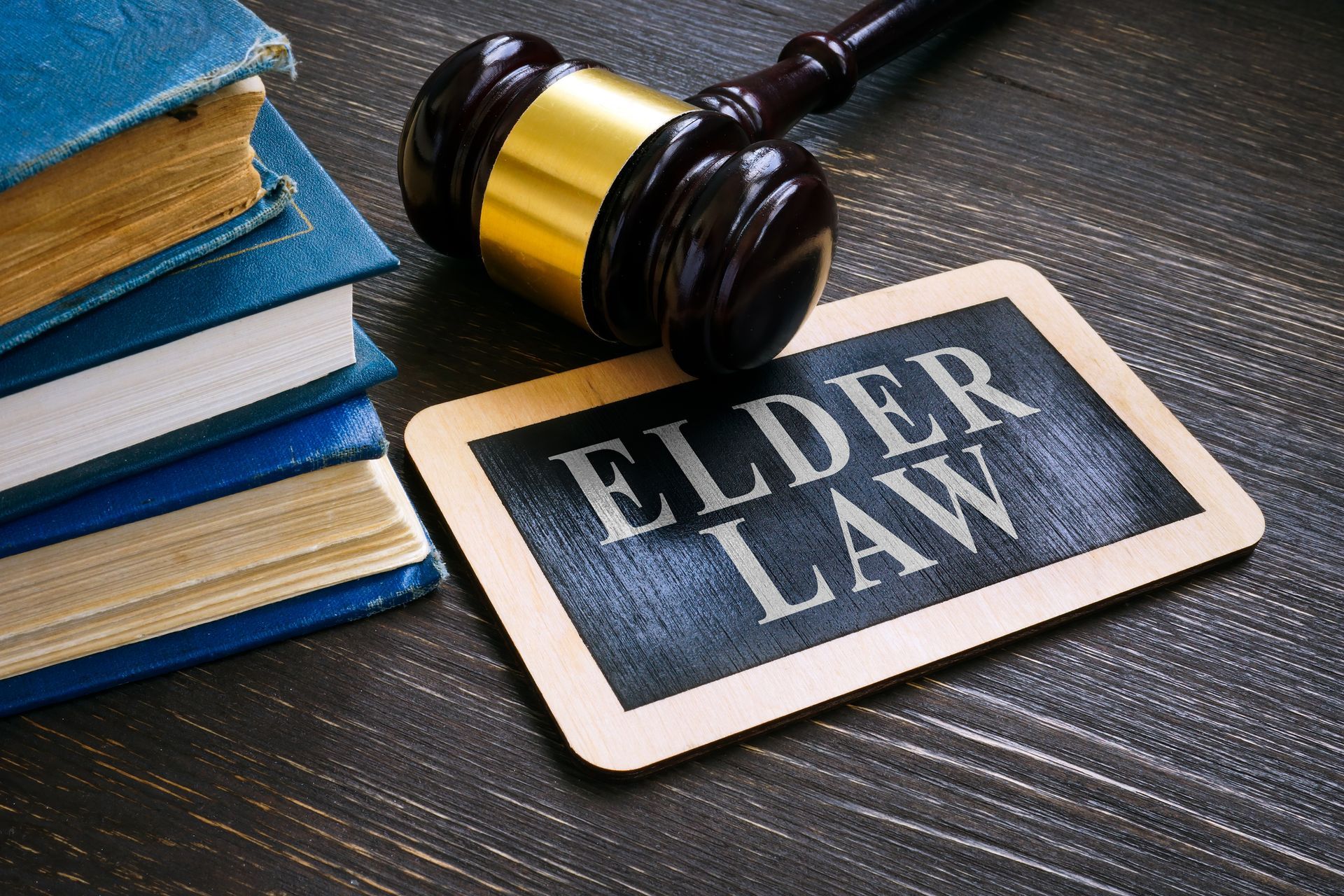 Gavel with elder law plate and books on a wooden desk.