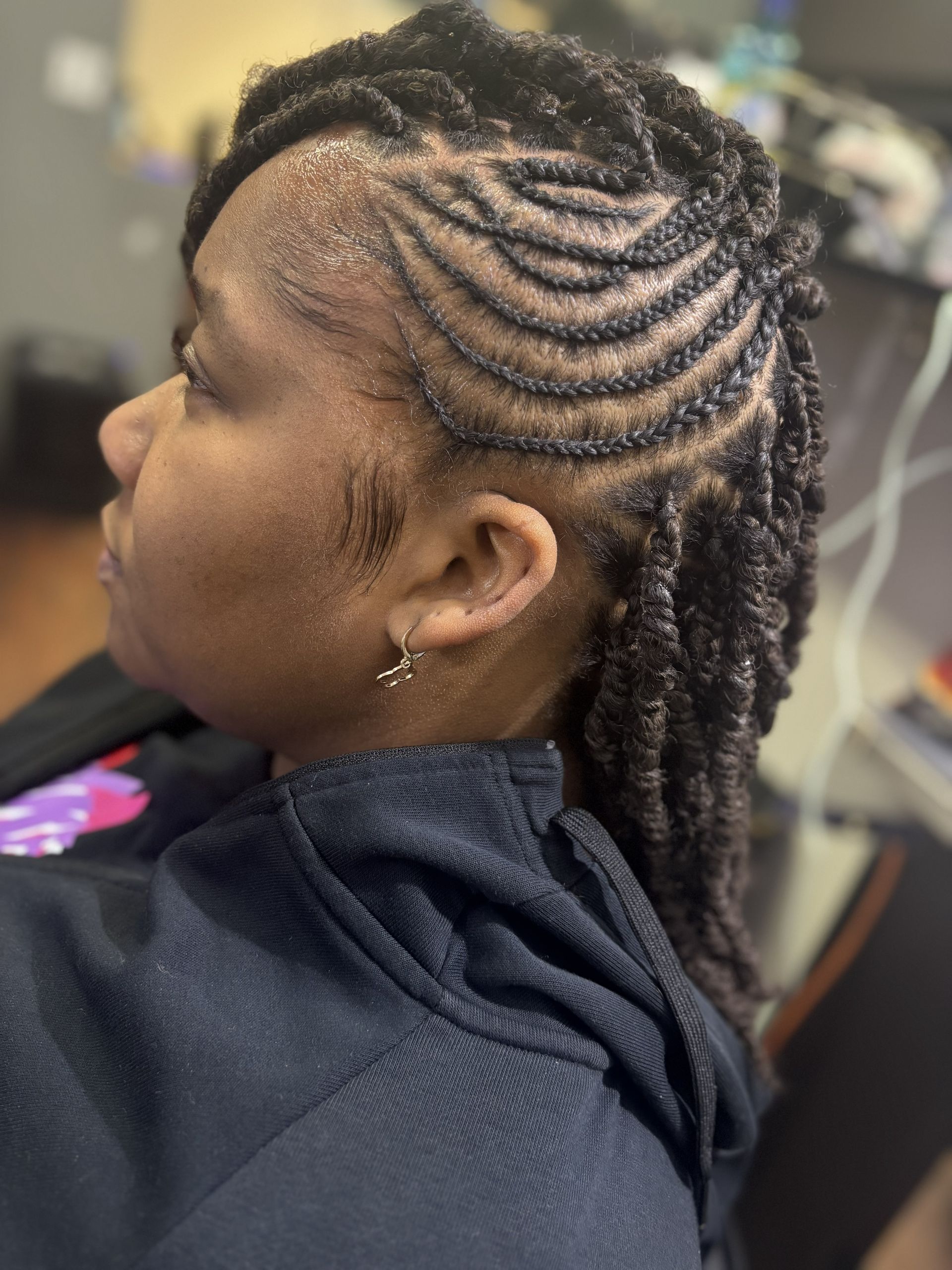 Side view of braided hairstyle with neat cornrows and long twists in a salon chair