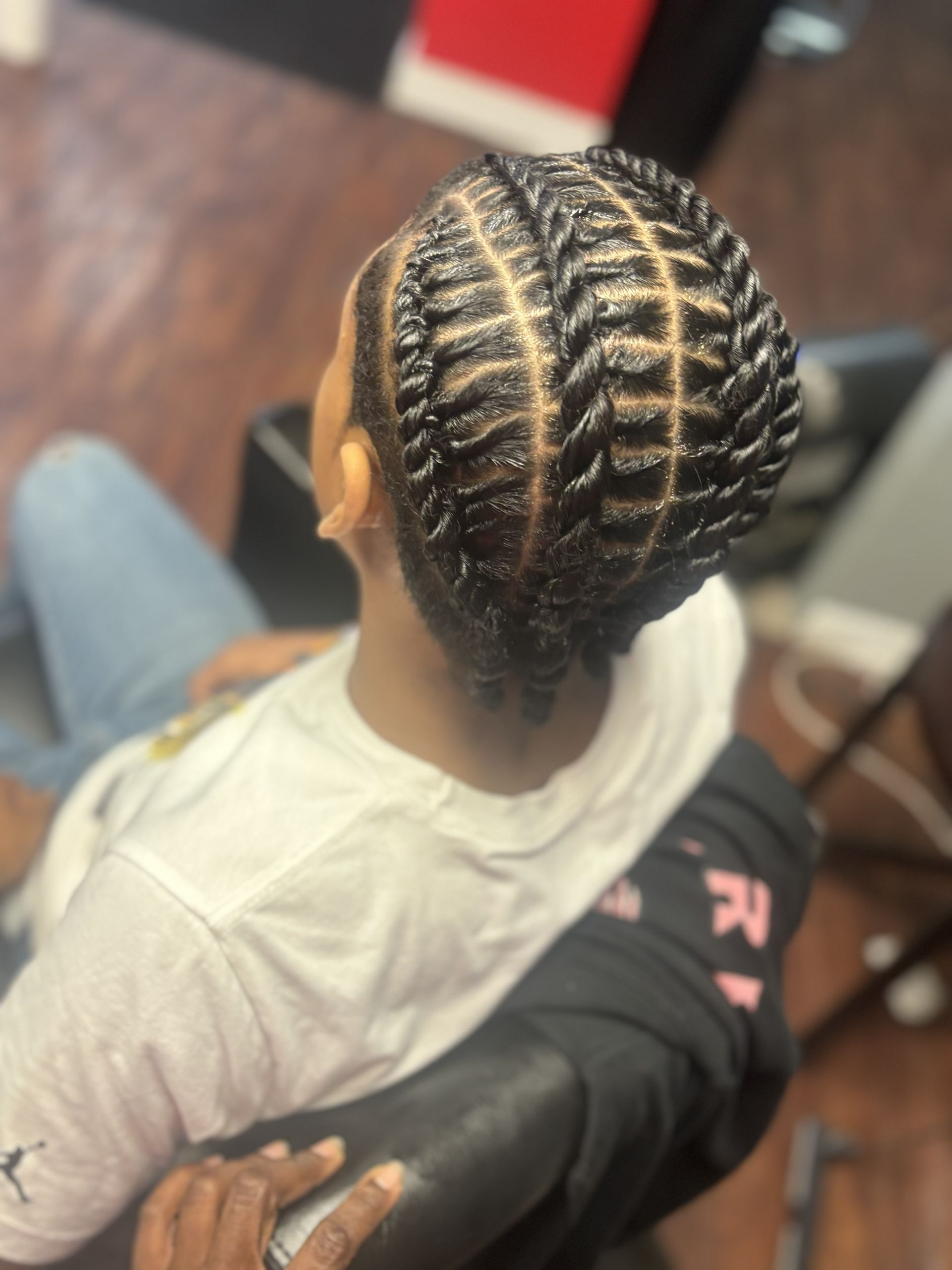 Braided hairstyle with neat cornrows, viewed from above while seated indoors.