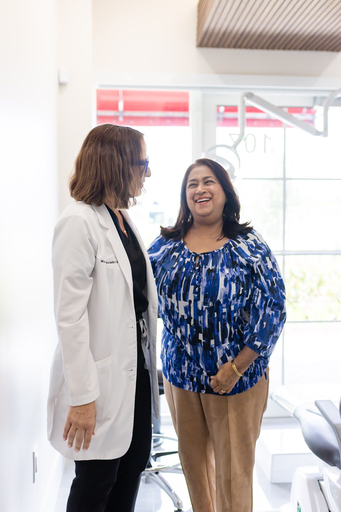 Dr. María Escabí and a smiling patient standing in a treatment room