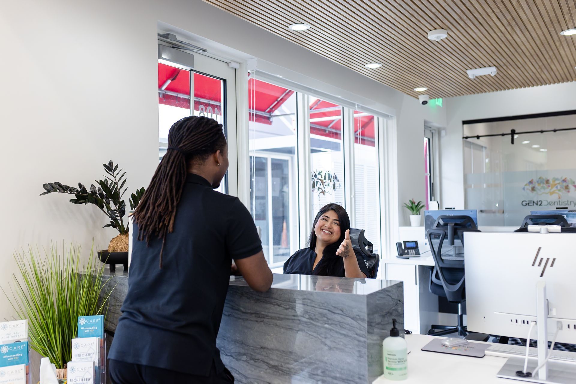 Front desk team helping a patient with insurance at GEN2 Dentistry
