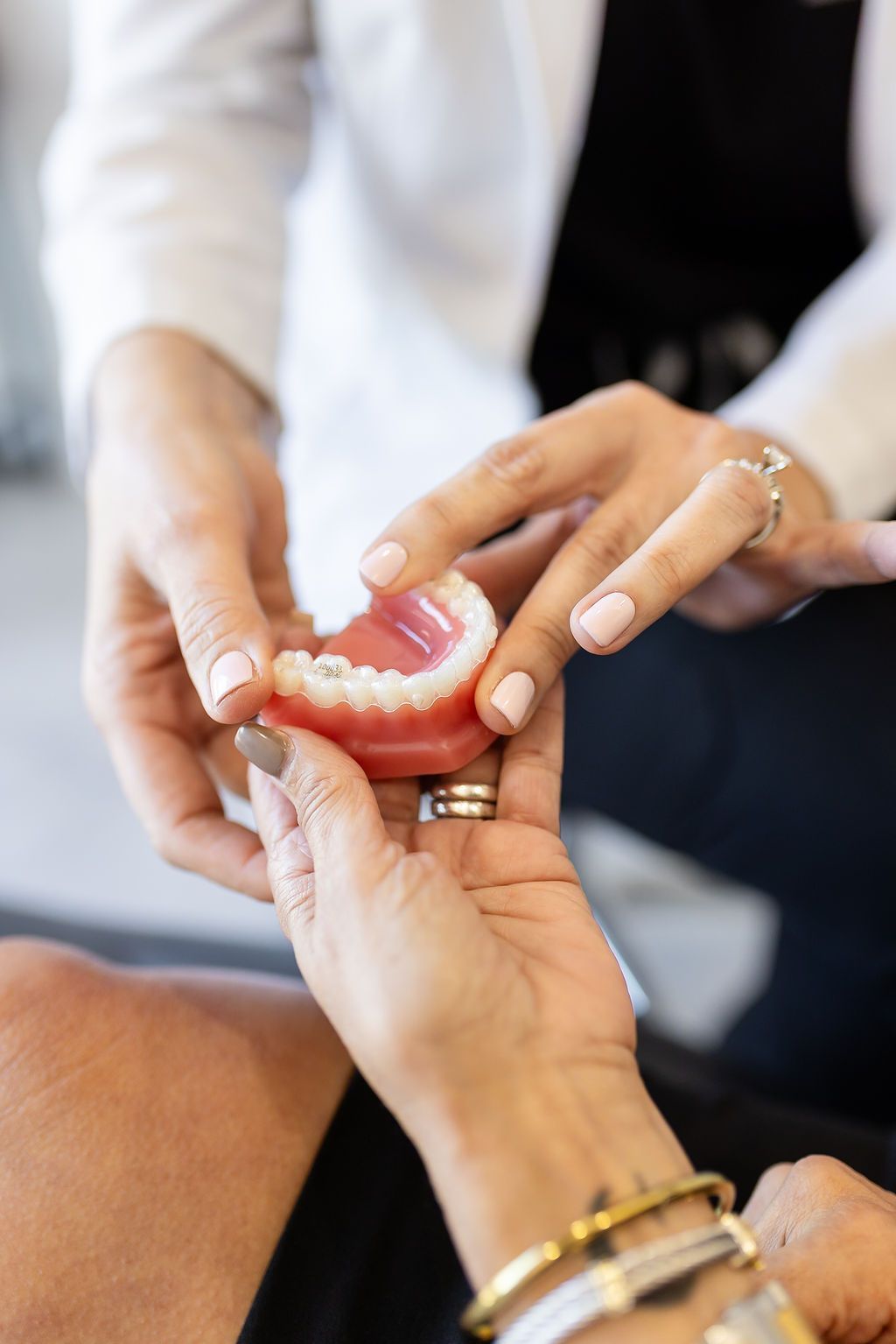 Dentist placing a denture in a patient's hands during a fitting