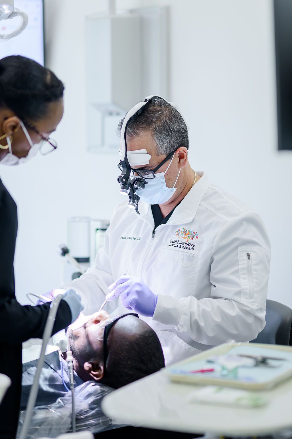 Dr. Paul Garcia with magnifying loupes caring for a patient in the chair