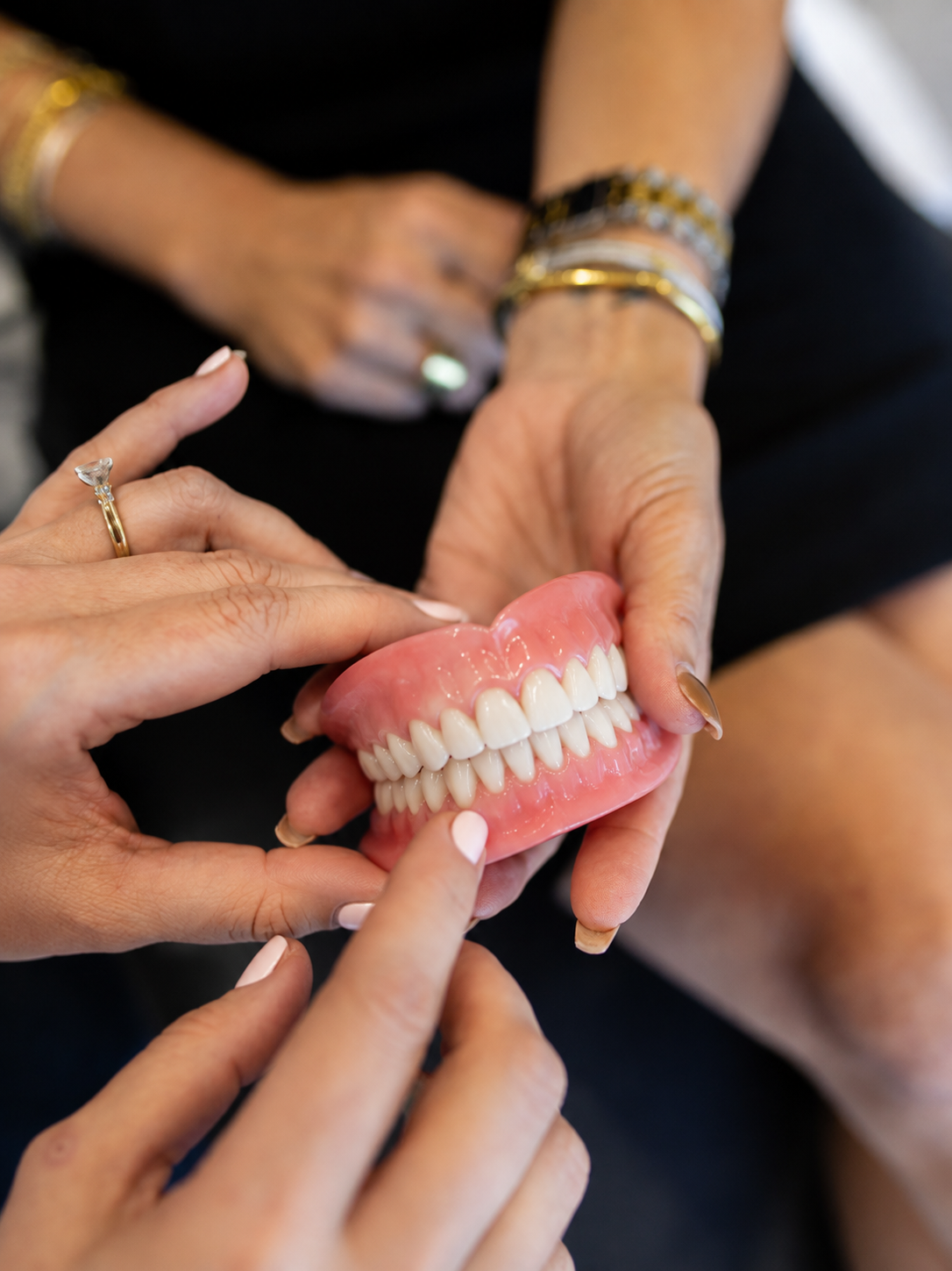 Hands holding a full set of dentures for a fitting