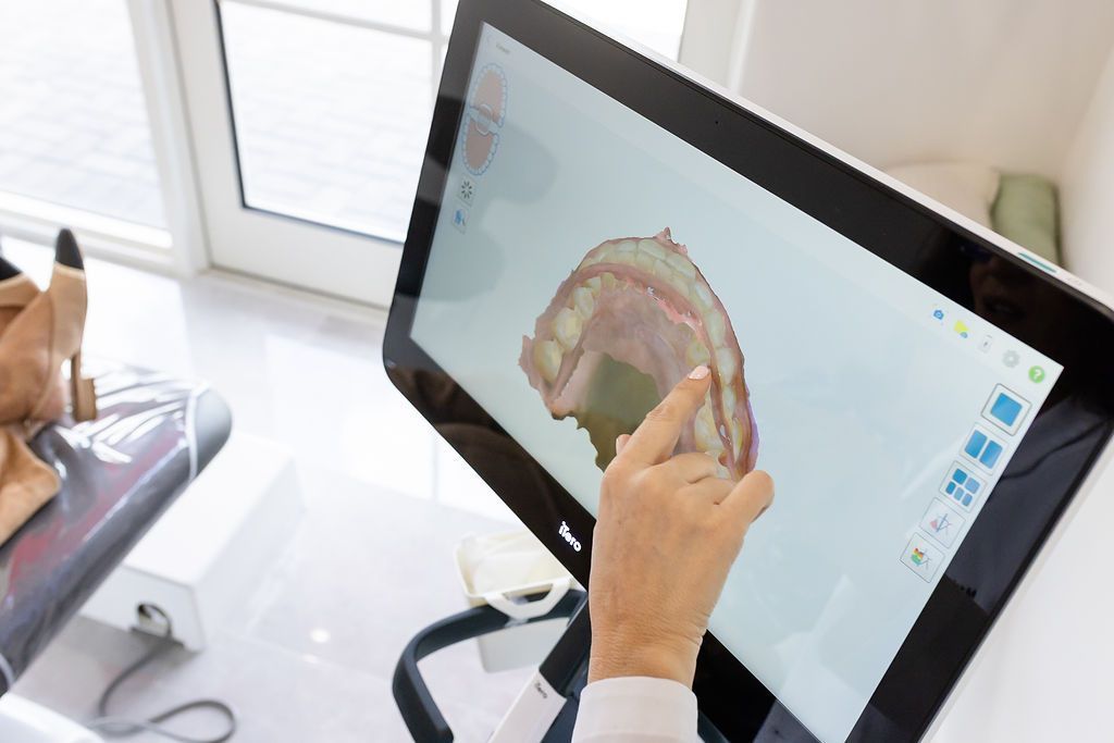 Dentist pointing to a 3D scan of the teeth and gums on a screen