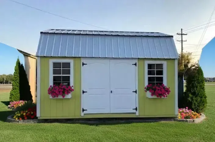 Small yellow garden shed with white doors, pink flower boxes, and a metal roof on a grassy lawn
