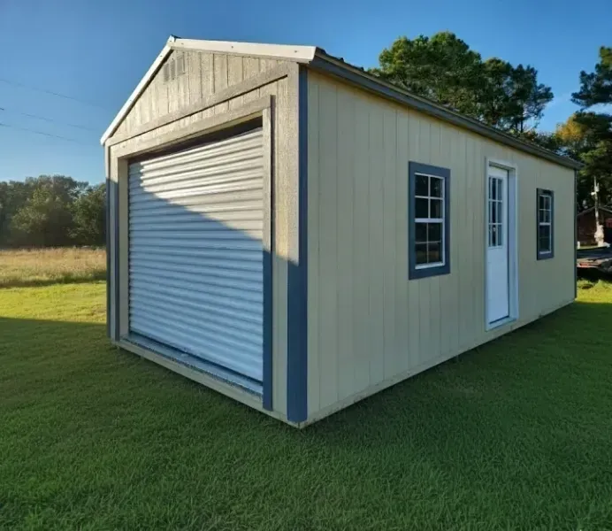 Small beige shed with a white roll-up garage door and side entry door on a grassy lawn.