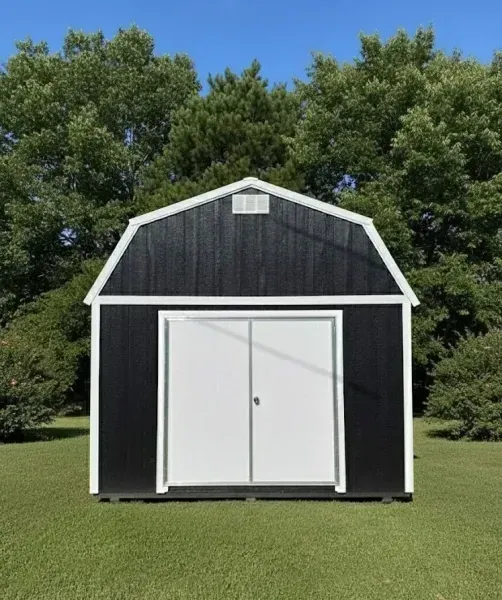 Black and white shed with double doors on a grassy lawn, trees in the background.