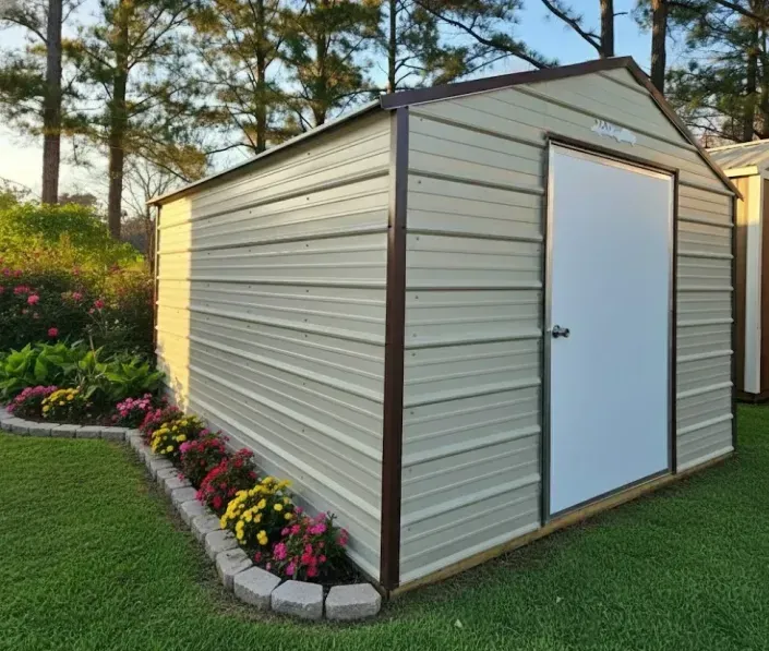 Small beige metal shed with white door, set on a manicured lawn with flowerbeds and trees around it.