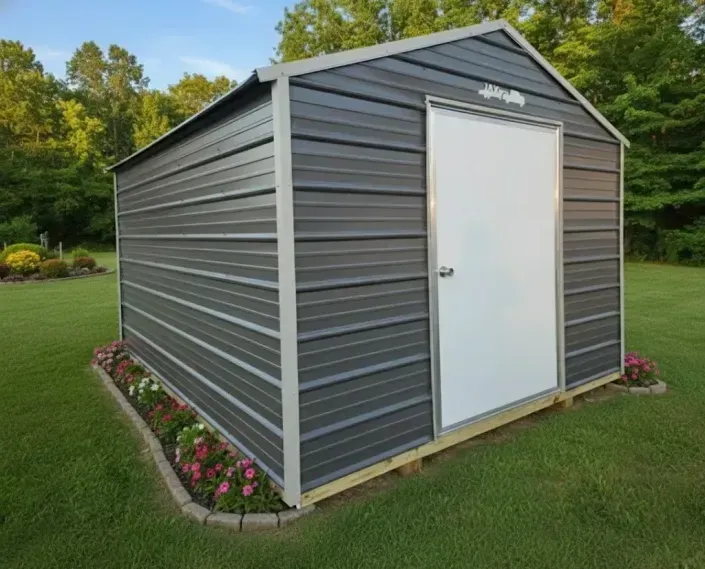 Gray metal storage shed with white door, set on a grassy lawn with flower border