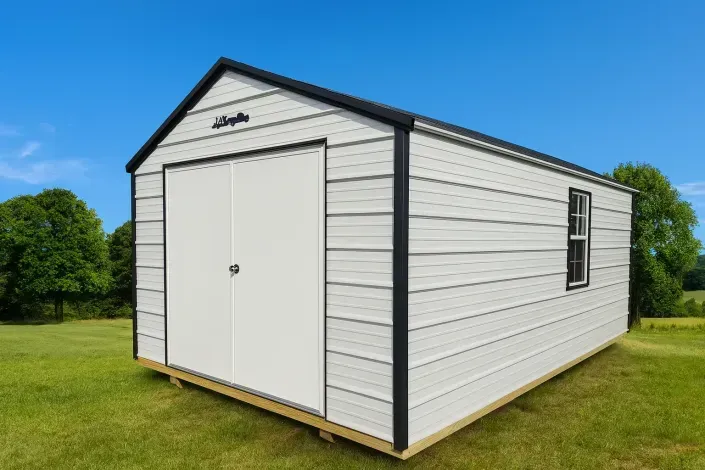 White portable shed with double doors on a grassy lawn under a blue sky