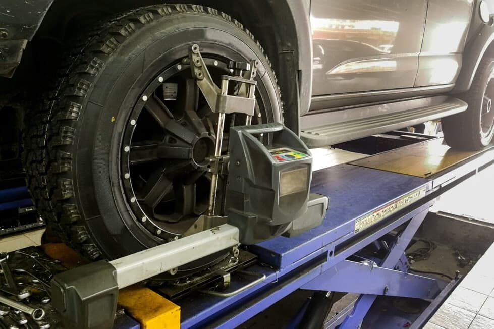 Black Truck Tire On A Lift With Alignment Equipment Attached — Darwin Auto Mobile Care in Woolner, NT