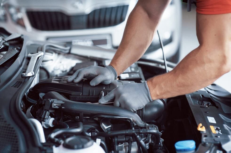 Mechanic Wearing Gloves Working On A Car Engine In A Garage — Darwin Auto Mobile Care in Woolner, NT