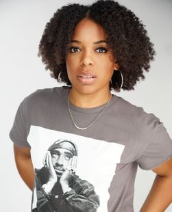 Person wearing a gray graphic T-shirt, standing against a light background with hands on hips.