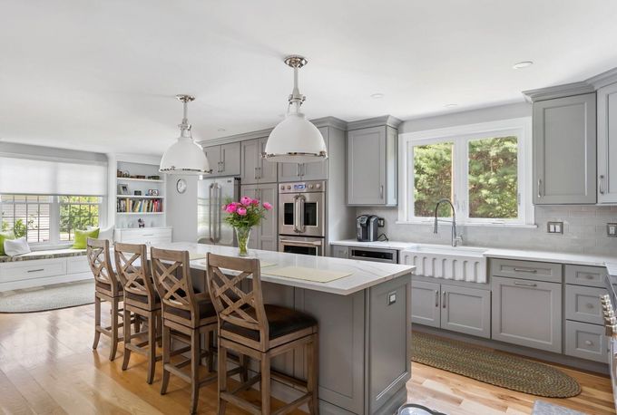 A kitchen with gray cabinets , white counter tops , and a large island.