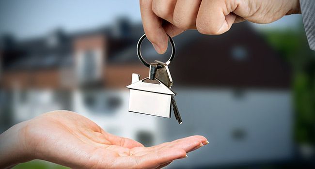 A person is handing a house key to another person.