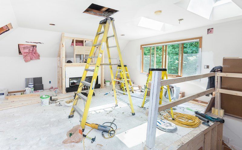 A living room is being remodeled with a ladder in the middle of the room.