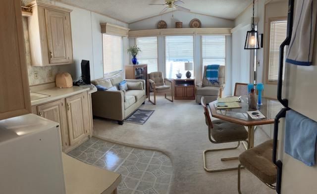 Bright RV interior with beige cabinets, couch, small table, and front windows with blue chairs
