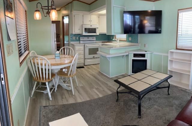 Bright mint-green kitchen and dining area with white cabinets, round table, and wall-mounted TV