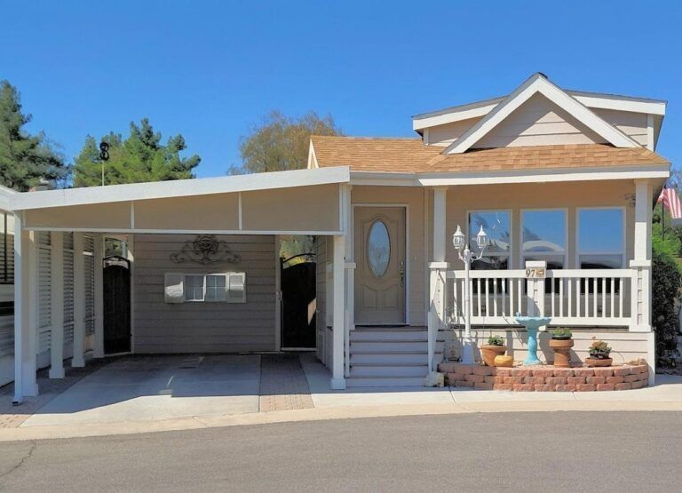 Single-story house with carport, front porch, and white trim under a clear blue sky