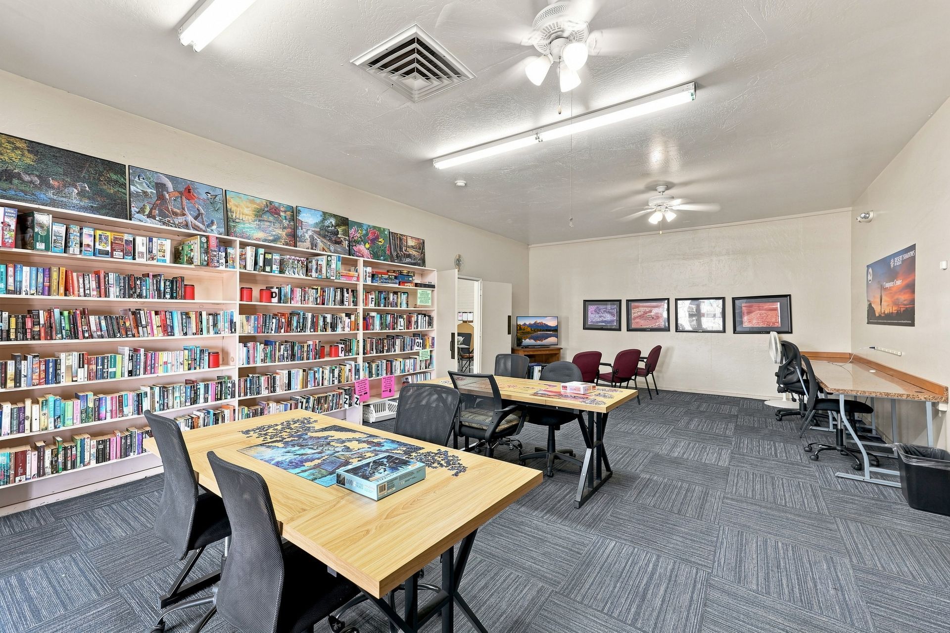 A room with long white bookshelves filled with books and a folding table in the foreground.