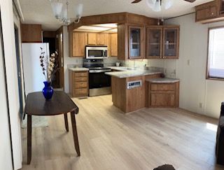 Bright kitchen and dining area with wood cabinets, light flooring, and a small table with a blue vase.