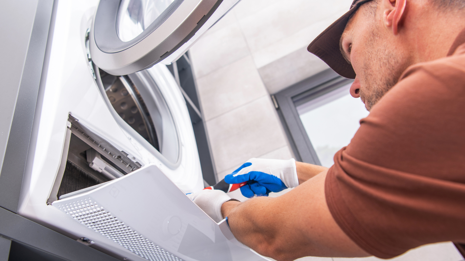 A man is working on a washing machine in a bathroom.