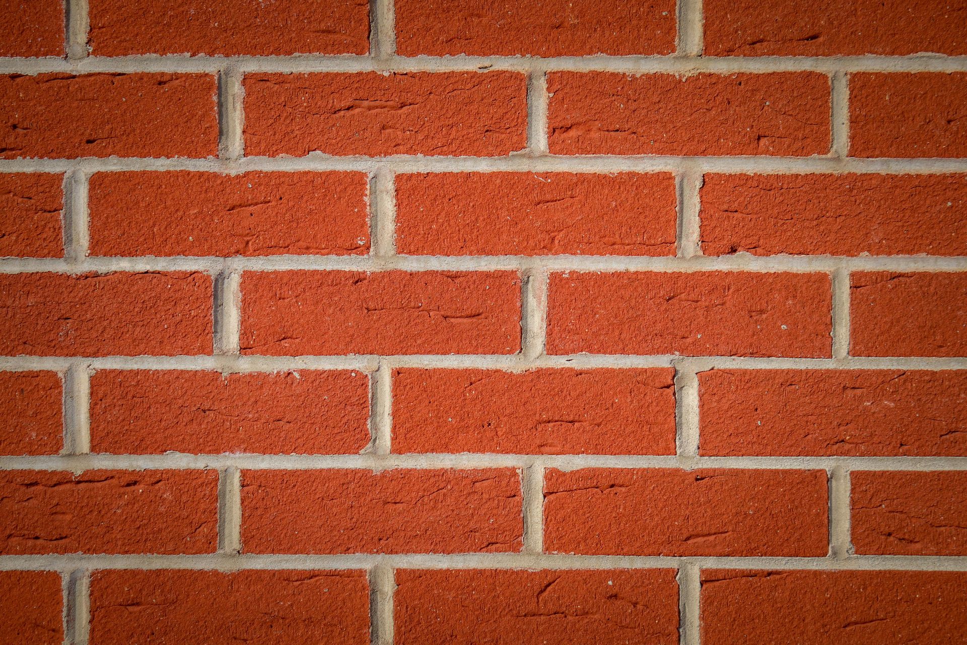 Red brick wall with light gray mortar lines and rough textured surface