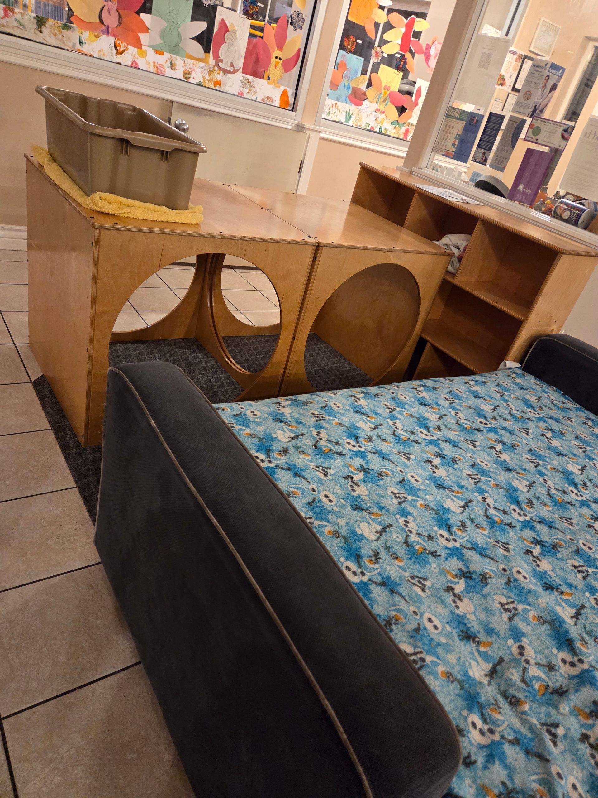 Blue patterned couch beside a small wooden table with circular cutouts in a tiled room