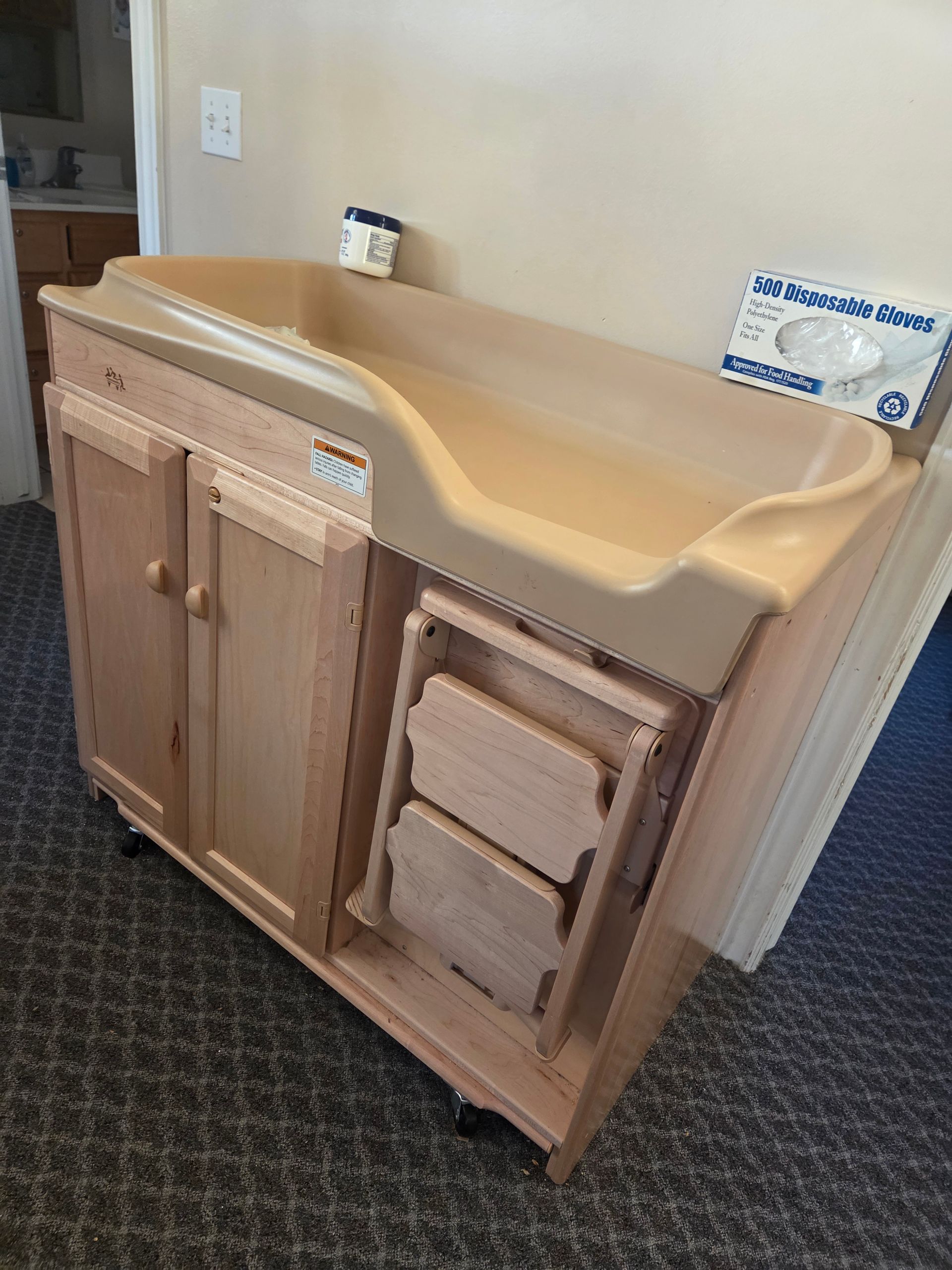 Accessible changing table with sink and fold-out child seat in a room