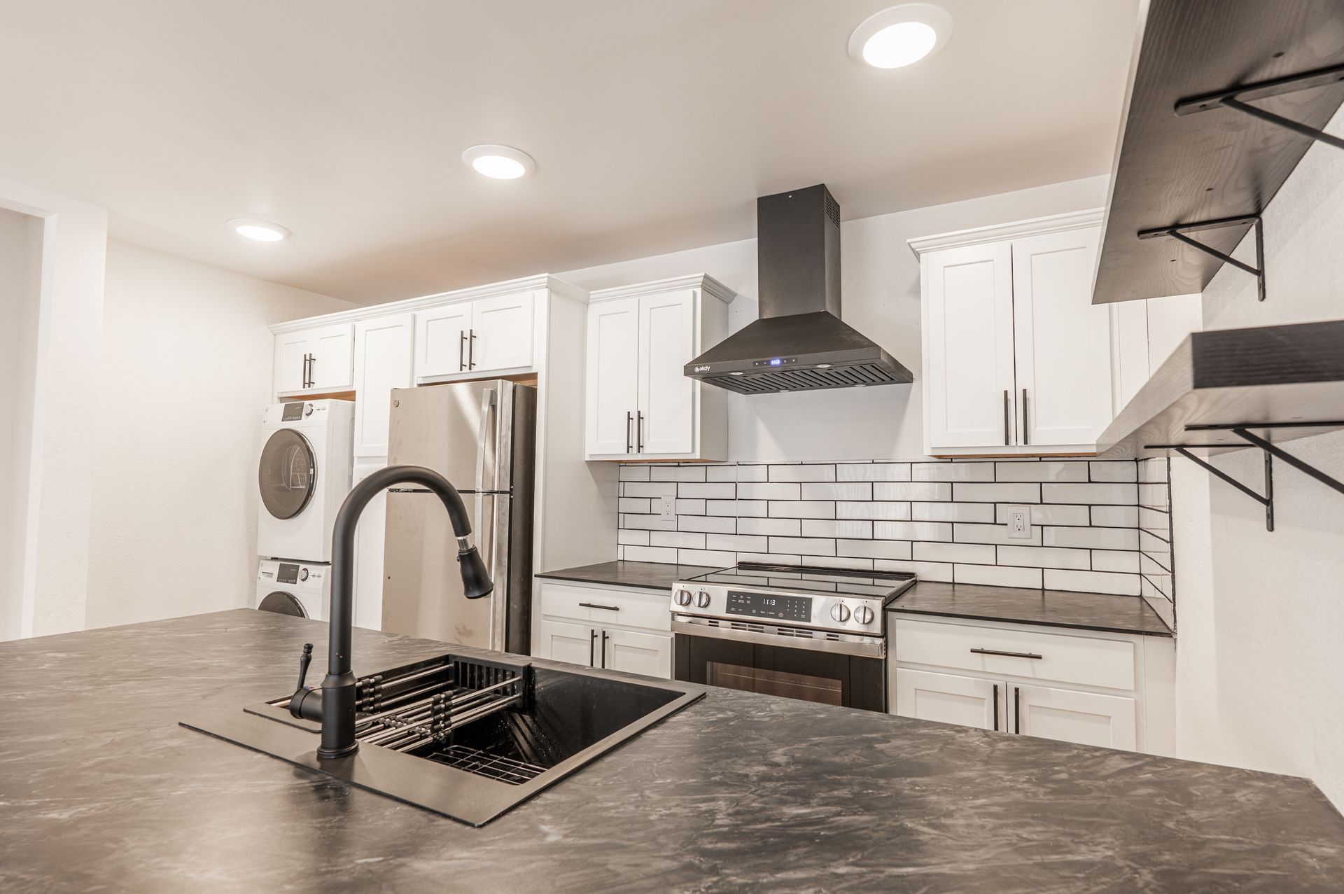 Kitchen with stainless steel appliances, white cabinets, and dark countertops.