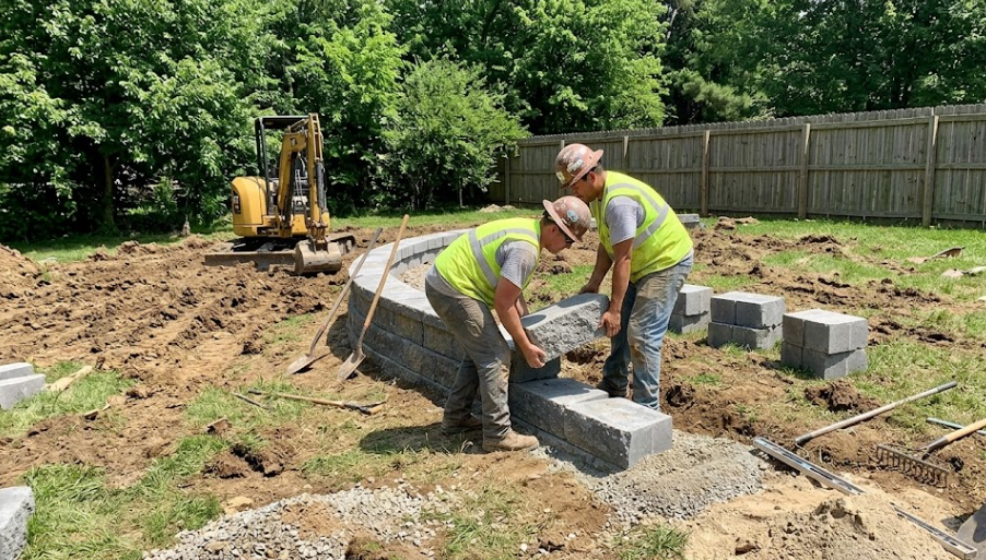Retaining wall builder installing interlocking concrete blocks for a residential hardscape project