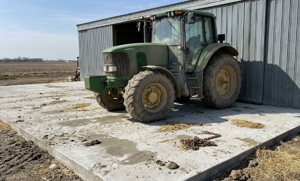 Heavy farm tractor parked safely on a durable concrete storage pad.