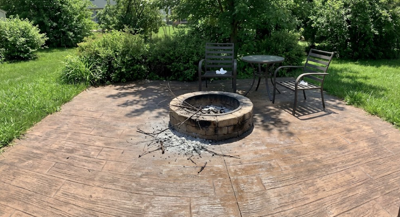 Stamped concrete backyard patio designed to look like brown wood planks with outdoor seating.