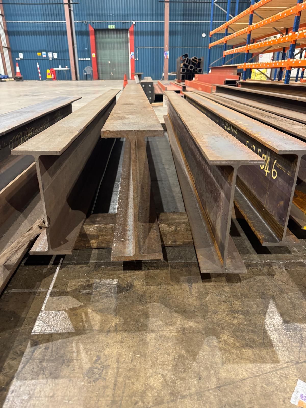 Four steel rsj beams on the floor in a warehouse
