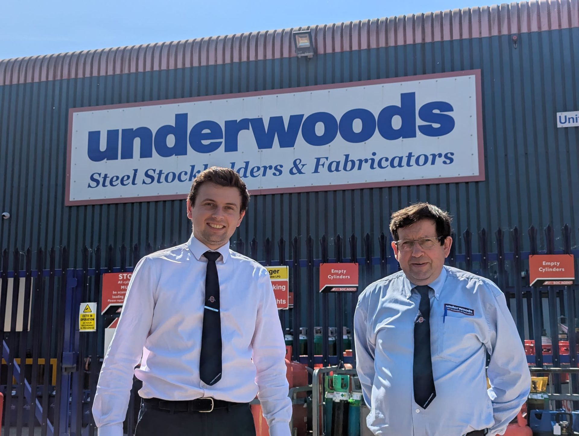 Two men - Will and Mark Underwood -stood outside of the Underwoods, Steel Centre in Worcester  warehouse.
