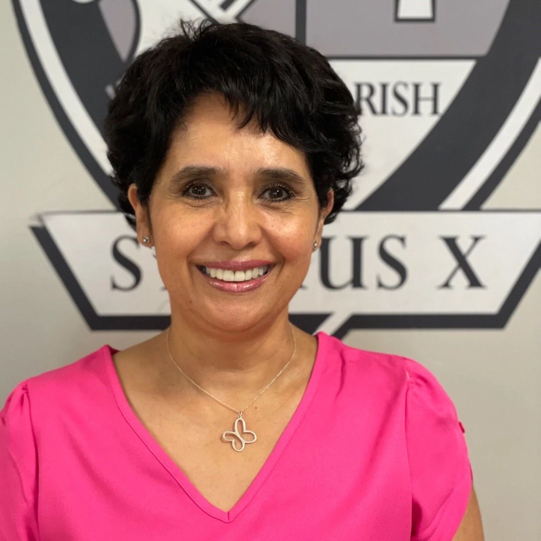 A woman in a pink shirt is smiling in front of a logo.