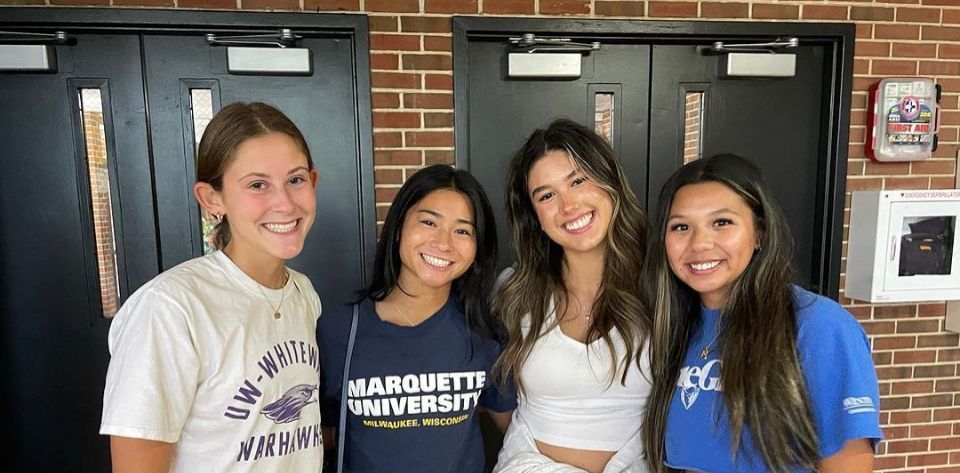 A group of young women are posing for a picture in a hallway.