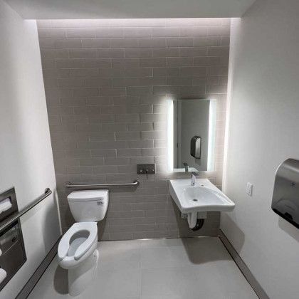 A bathroom with a toilet , sink and mirror.