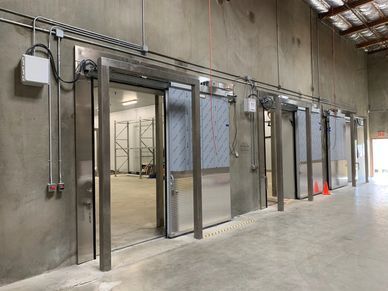 A row of stainless steel sliding doors in a warehouse.