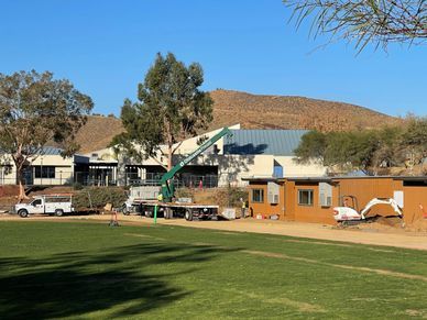 A large building is being built in the middle of a grassy field.