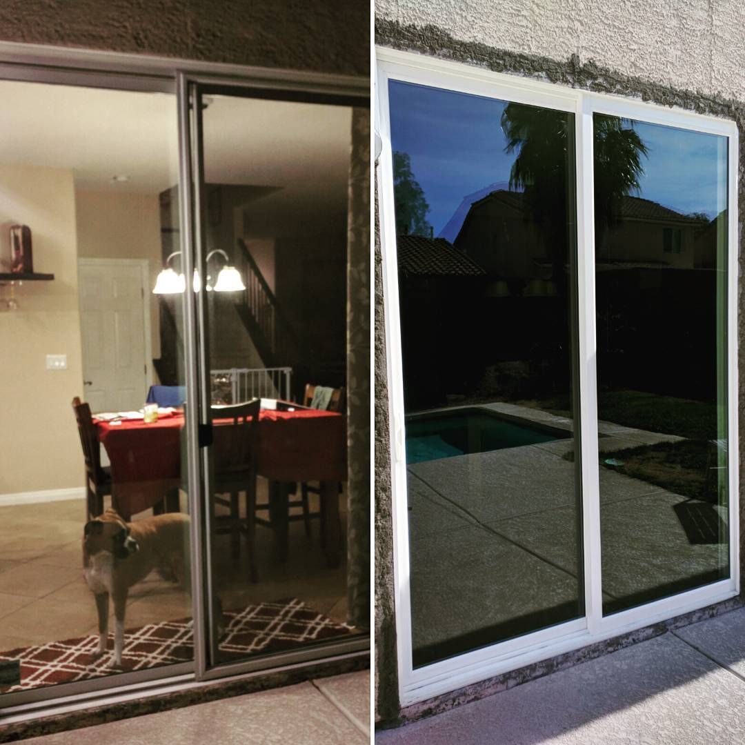 Sliding glass doors reflecting a dining room and a backyard patio at dusk