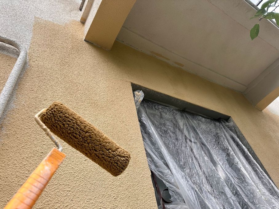 Broom and dustpan leaning against a stucco wall beside a covered doorway outdoors