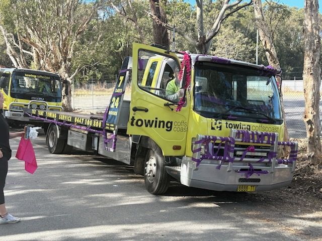 A Yellow Tow Truck Parked on a Paved Area Near Trees — TCC Towing Coffs Coast in Harbour, NSW